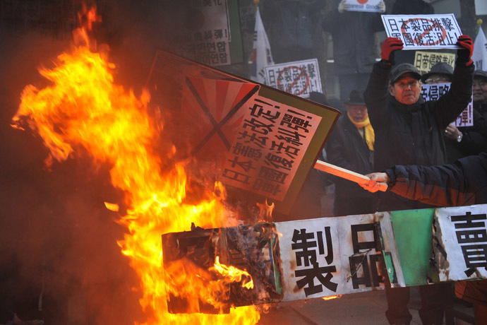 South Korean conservative activists set fire to effigies of Japanese Prime Minister Shinzo Abe during a protest to lodge a complaint against Abe visiting the Yasukuni war shrine to mark the first anniversary of his taking office, in Seoul on December 27, 2013. (AFP Photo/Woohae Cho)